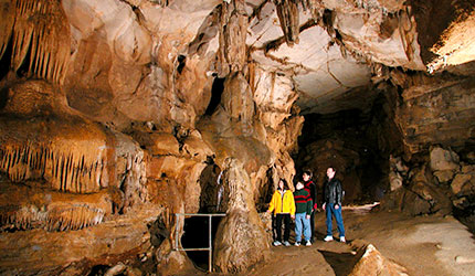 Outlaw Cave scene with family among cave formations on pathway.